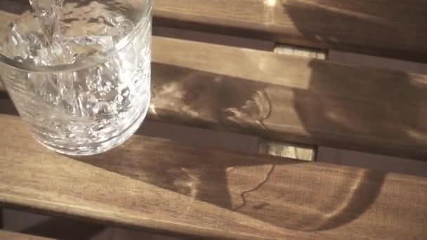 Вихор води в склянці на столі повільний рух — стокове відео
