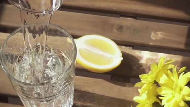 El agua pura de cámara lenta fluye maravillosamente en el vaso sobre la mesa — Vídeos de Stock
