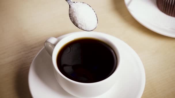 Le sucre d'une cuillère est versé dans une tasse au ralenti 