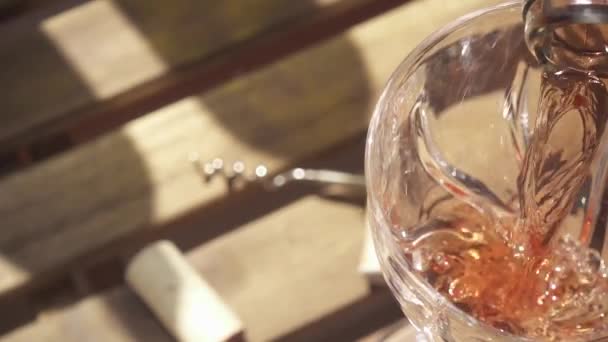 Медленное движение вина из горлышка бутылки течет в стакан на столе — стоковое видео