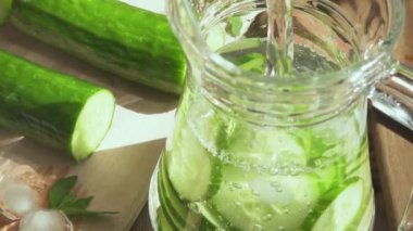 Yavaş hareket su bir sürahi dilimlenmiş salatalık ile içine dökülür