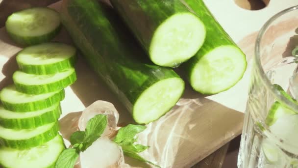 Slow motion water is poured into a glass with ice and cucumber — Stock Video