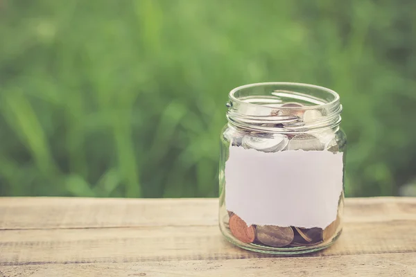 Money in the jar on wooden table — Stock Photo, Image