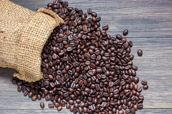 The sack of coffee beans on wooden background — Stock Photo, Image