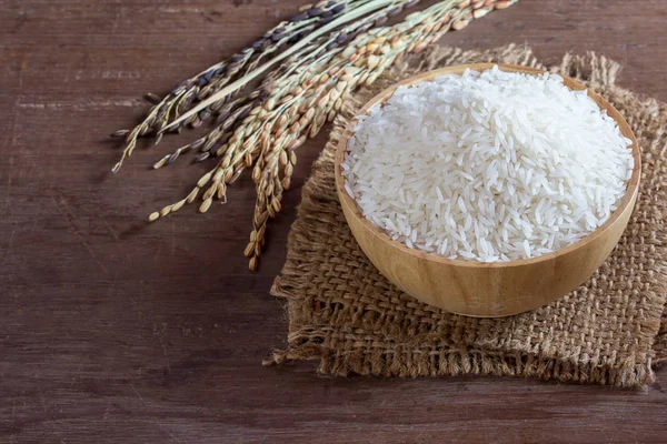 Jasmine rice in bowl and sack on old wooden table — Stock Photo, Image