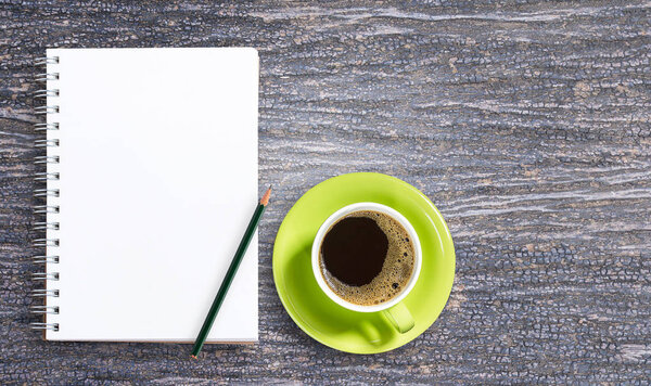 Blank notepad and pencil with cup of coffee on wooden