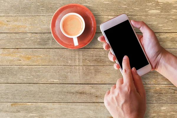 Handen håller smart telefon med träbord bakgrund. — Stockfoto