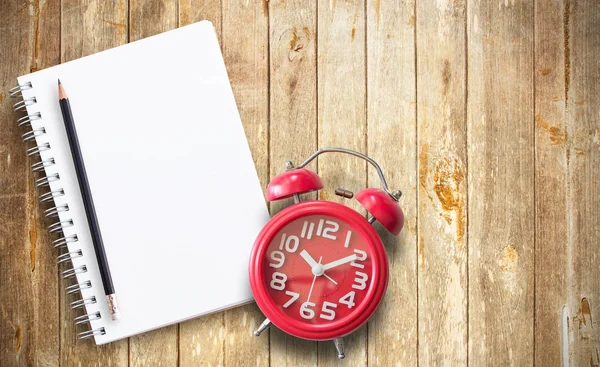 Reloj despertador rojo y libreta de notas en madera marrón —  Fotos de Stock