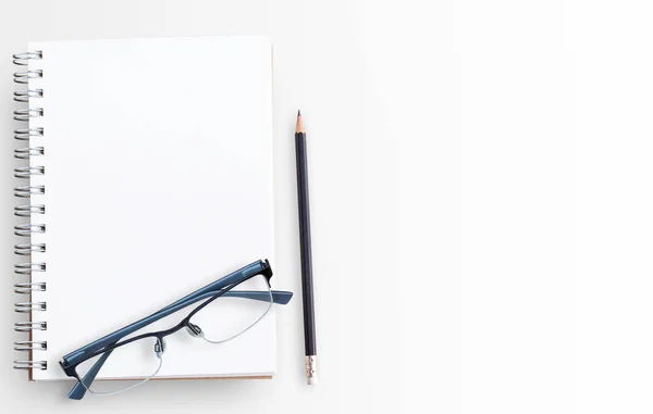 Caderno de papel em branco e óculos no fundo da mesa branca — Fotografia de Stock