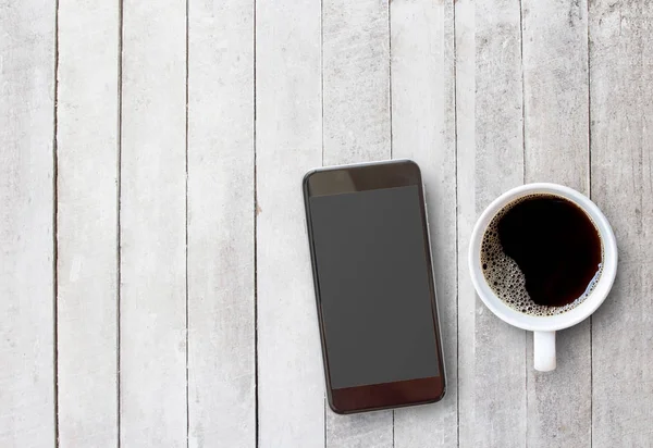 Smart telefon och kopp kaffe på gamla trä bakgrund med cop — Stockfoto