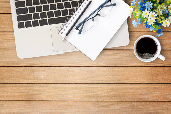 Wood office desk table with notebook,flower, cup of coffee and g