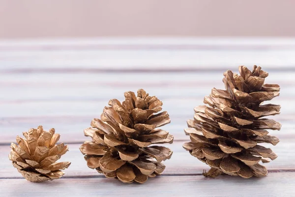 Close up cones de pinho de ouro em um fundo de mesa de madeira branca . — Fotografia de Stock