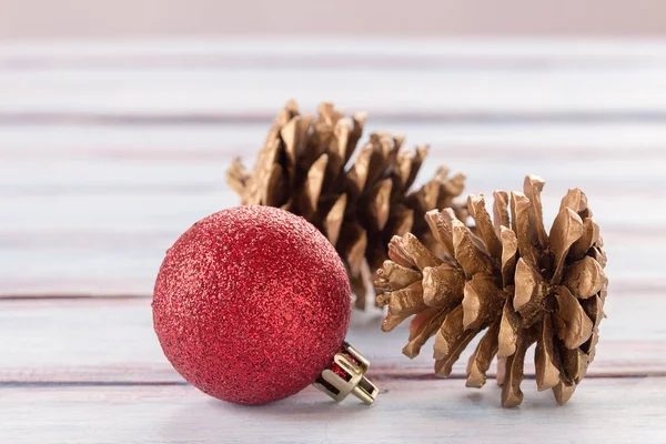 Ta Noel top ve bir beyaz tahta üzerinde altın çam kozalakları kapatın — Stok fotoğraf