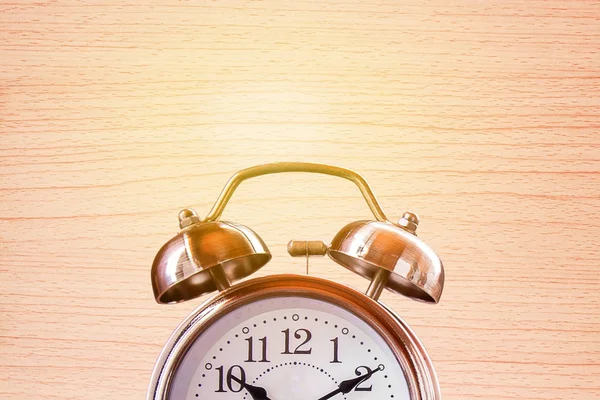 Close up retro alarm clock on a wooden table with blurred brick — Stock Photo, Image