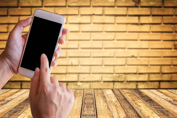 Empresário segurando smartphone com parede de tijolo borrada e madeira — Fotografia de Stock