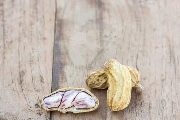 Geröstete oder gereihte Erdnüsse auf rustikalem, dunklem Holztisch verstreut — Stockfoto