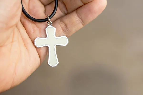 Christian cross in hand with blurred bokeh light background