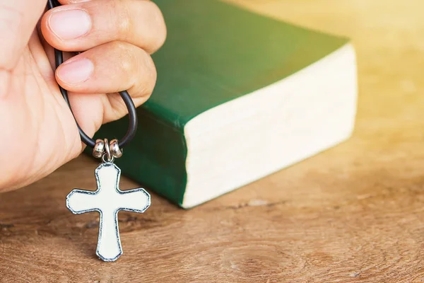 Cruz cristiana en la mano con fondo bíblico — Foto de Stock
