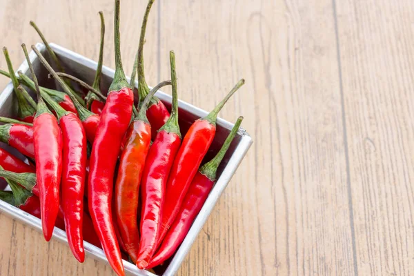 Red chili in cup and chilli peppers on a wood table — Stock Photo, Image