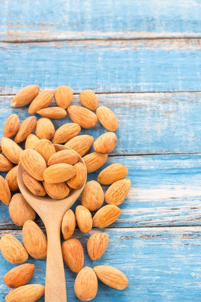 Peeled almonds in wooden spoon on wood background.