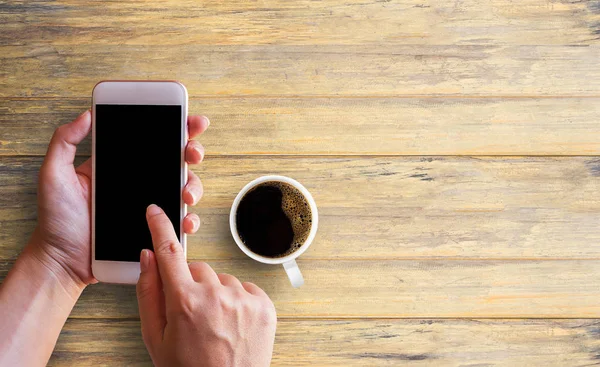 Kvinnlig hand med smartphone vit skärm och kopp kaffe på w — Stockfoto