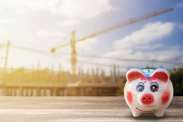 Piggy Bank op houten bureau en onscherpte bouw achtergrond. — Stockfoto