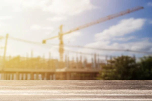 Escritorio de madera y fondo de construcción borrosa . — Foto de Stock