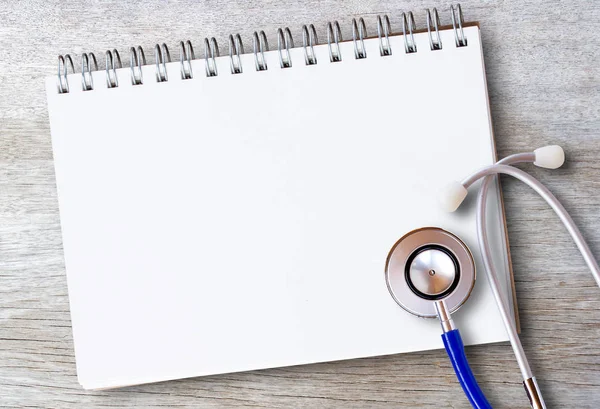 Medical healthy equipment. Workplace of a doctor. Stethoscope and notebooks on wooden desk background.Top view with copy space for design. Business health and medical concept.