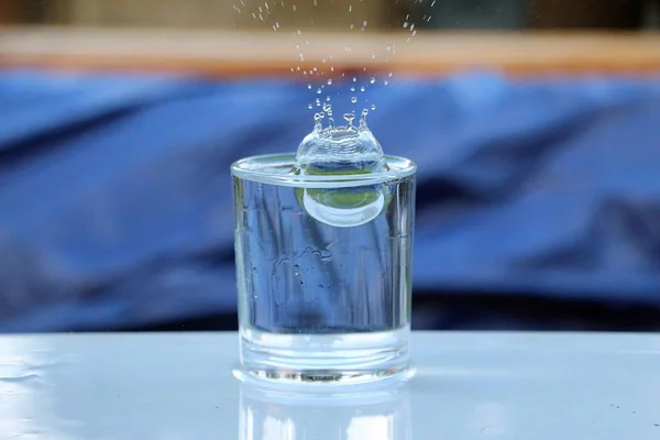 Esőcseppek Beleesnek Egy Pohár Vízbe Ami Asztalon Áll Kertben — Stock Fotó