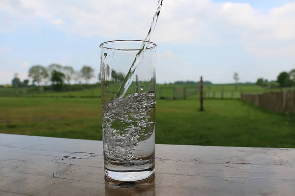 Frischwasser Fällt Ein Glas Das Auf Einem Tisch Garten Steht — Stockfoto