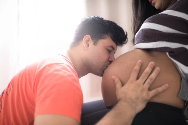 年轻的父亲亲吻怀孕的妻子的腹部 — 图库照片