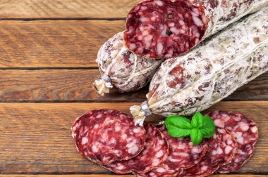 Tahta arka planda fesleğen yapraklı lezzetli İtalyan salamı.