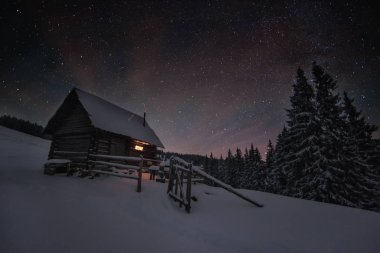 Kış dağında eski bir kulübeyle gece sahnesi