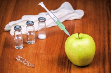 Aşı şırıngası ve sulu elma. Genetik modifikasyon teması