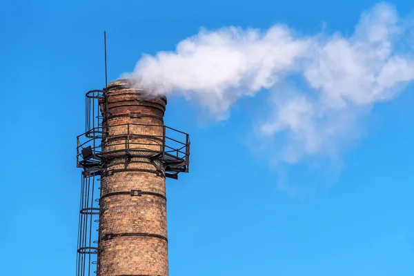 industrial pipe with smoke and blue sky