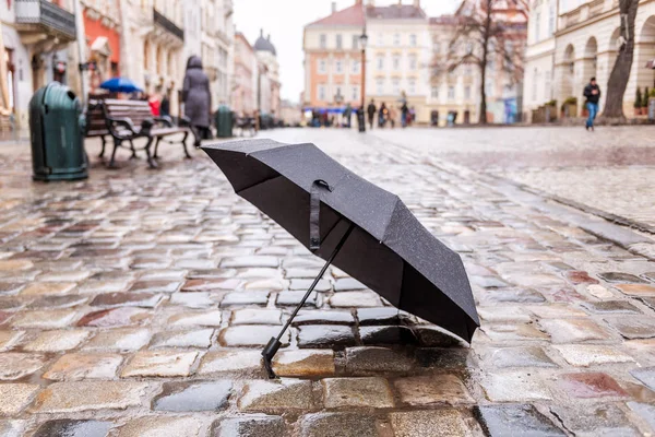 Schwarzer Regenschirm auf dem Bürgersteig — Stockfoto