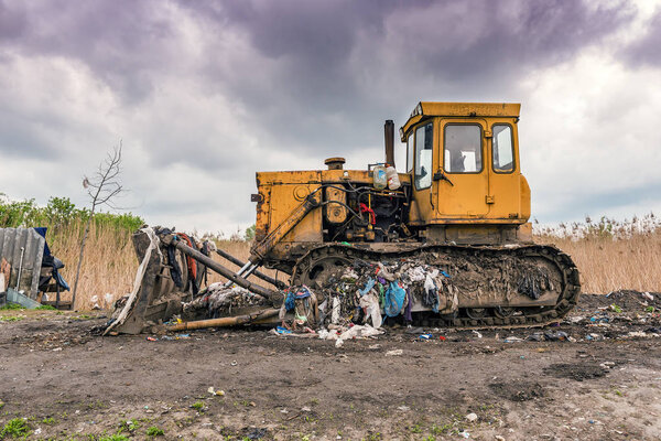 dirty yellow bulldozer on the garbage dump