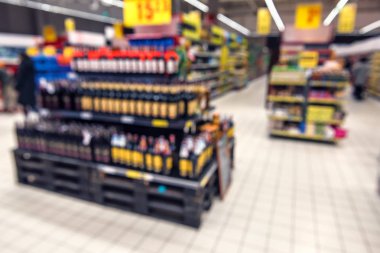 Renkli rafları ve tanınmayan müşterileri olan soyut bulanık süpermarket koridoru
