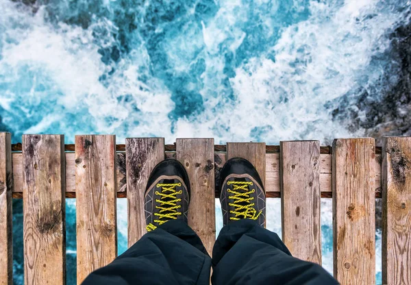 Fötter i stövlar på kanten av en gammal träbro — Stockfoto
