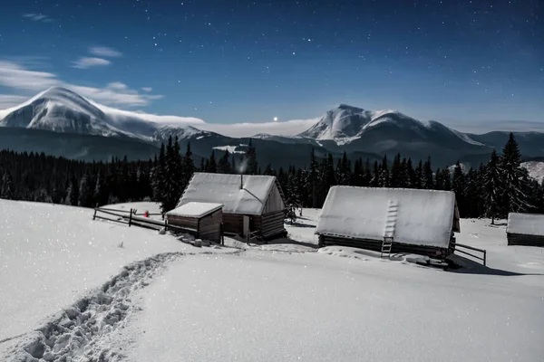 snow-covered cabins under moon light in the mountains