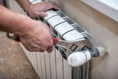 adjustable wrench repairs a heating radiator