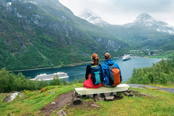Couple of tourists are sitting on the bench over Geiranger fiord — Stockfoto