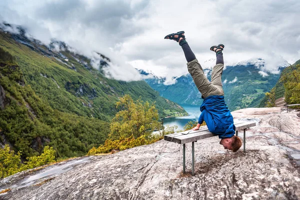 Guy doing the trick on the bench over Geiranger fiord — Stockfoto