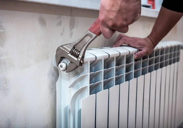 Adjustable wrench repairs a heating battery — Fotografia de Stock