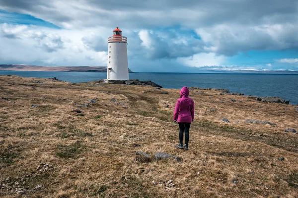 Tourist in bright jacket looks at the lighthouse — Stockfoto