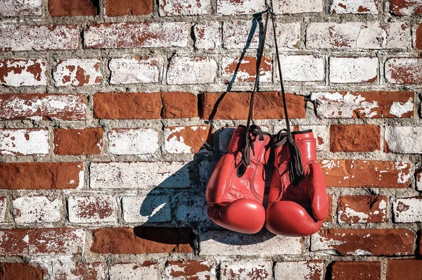 Červené boxerské rukavice na staré cihlové zdi — Stock fotografie