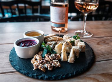 farklı peynir dilimleme parmesan, pecorino, dor blue, ceviz, lezzetli soslar, yeşil nane yaprağı ve bir şişe gül şarabı.