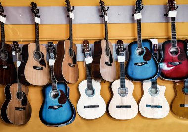 Duvarda farklı akustik gitarlar asılı.