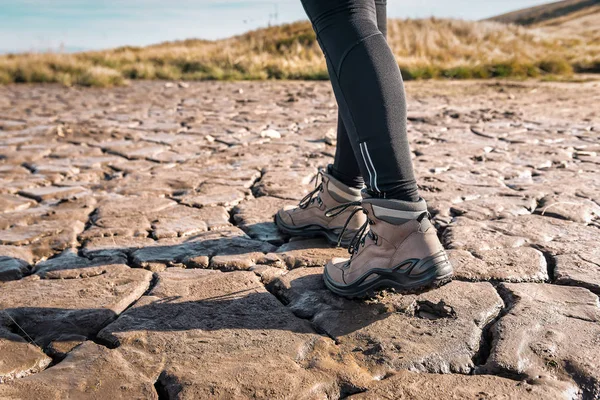 legs in hiking boots walks on swamp cracked soil