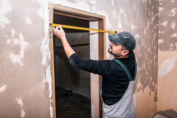 worker measures the doorway with the tape measure